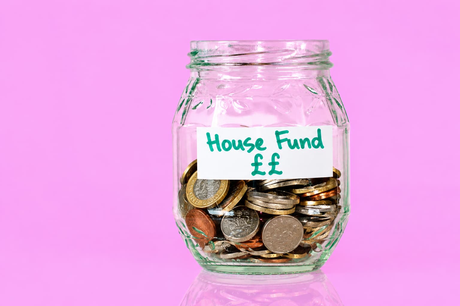 A glass jar labelled House Fund filled with UK coins, showing savings as a source of funds for a property purchase