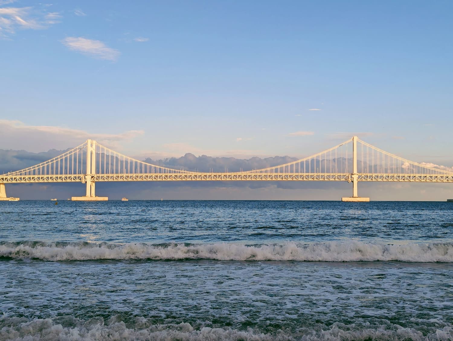 Sunlit suspension bridge spanning blue ocean waters, representing connection and continuity for a rebridging loan