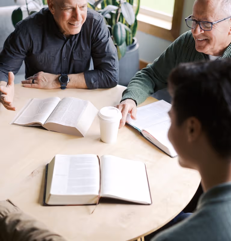 A group of men sitting around a table with open books.