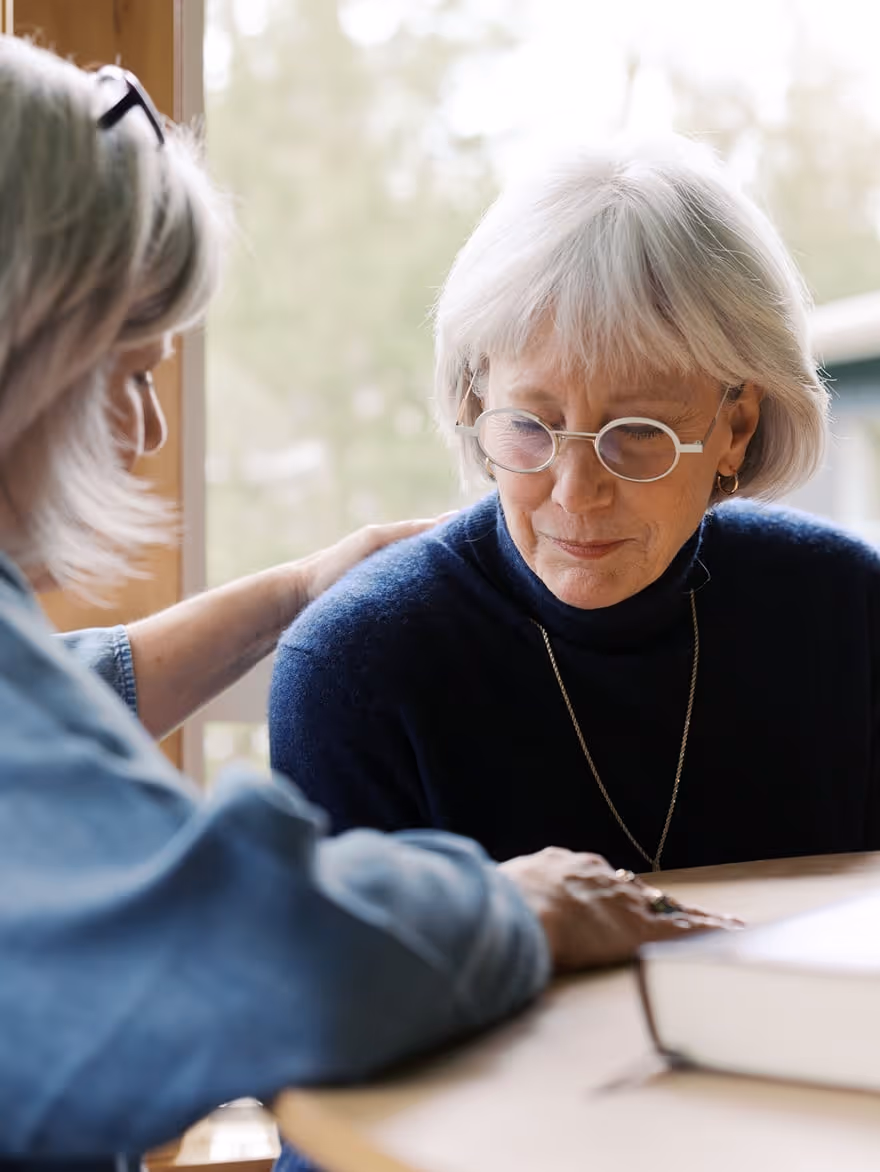 Two older women pray together.