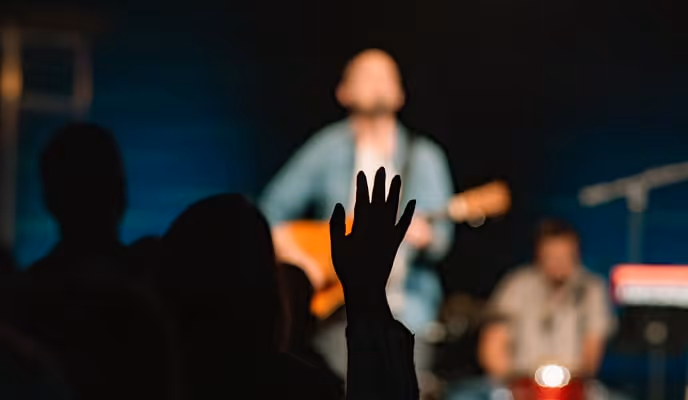 A person raising their hand in front of a band on stage