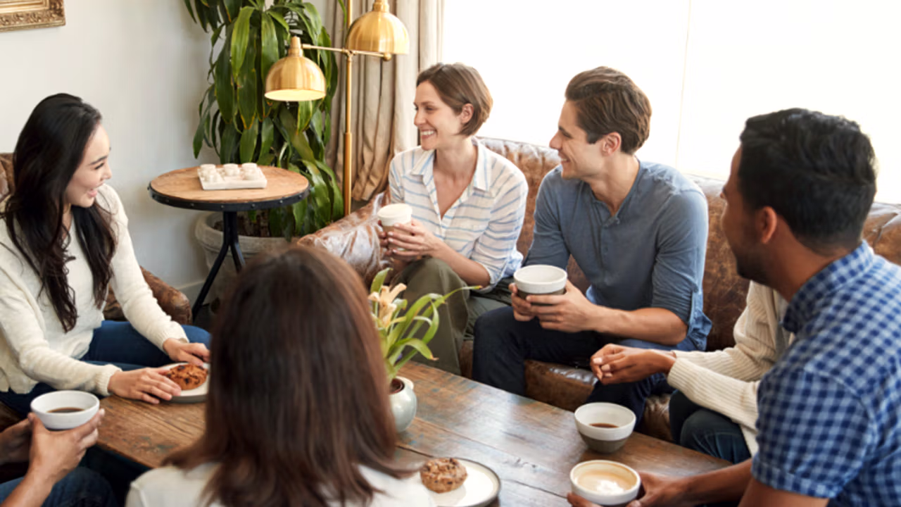 a group of men and women sit around a table talking