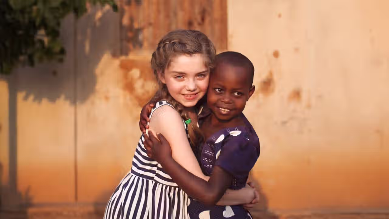 Two young girls embrace in a hug.