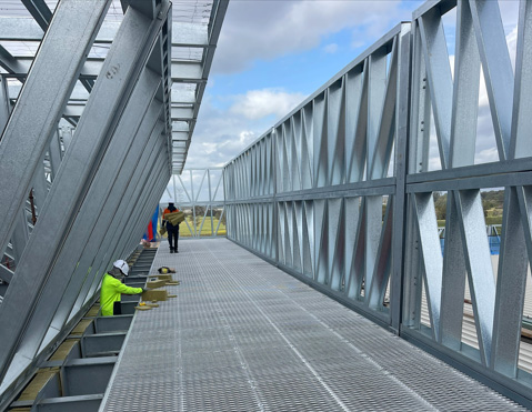 Steel-grating walkway between structural frames on a data centre rooftop.
