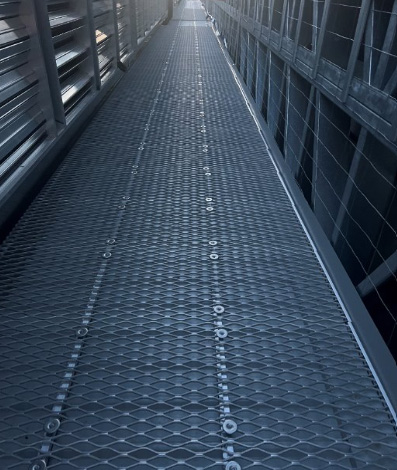 Narrow steel-grating walkway between dark data centre screens.