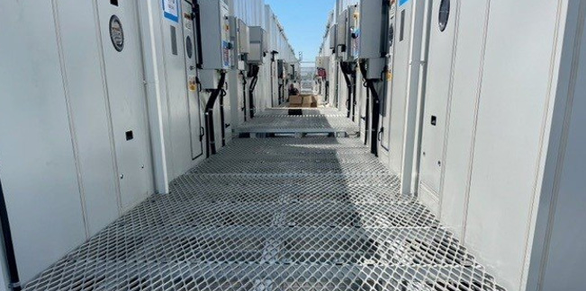 Steel-grating service walkway between data centre equipment units.