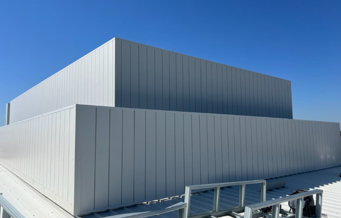 Grey acoustic enclosure surrounding rooftop mechanical equipment.
