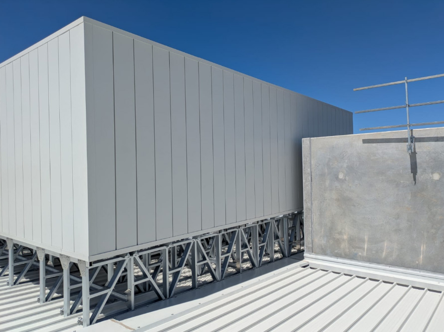 Grey acoustic enclosure installed beside a rooftop parapet.
