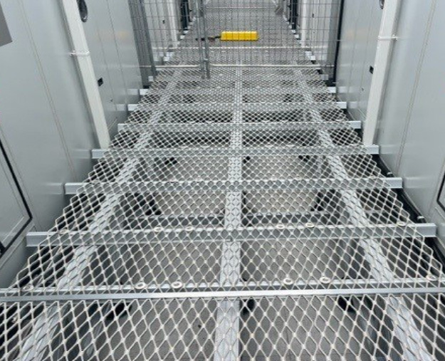 Close-up of a steel-grating access walkway between equipment units.