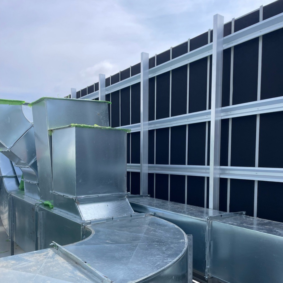 Curved metal ductwork beside an exterior data centre louvre wall.