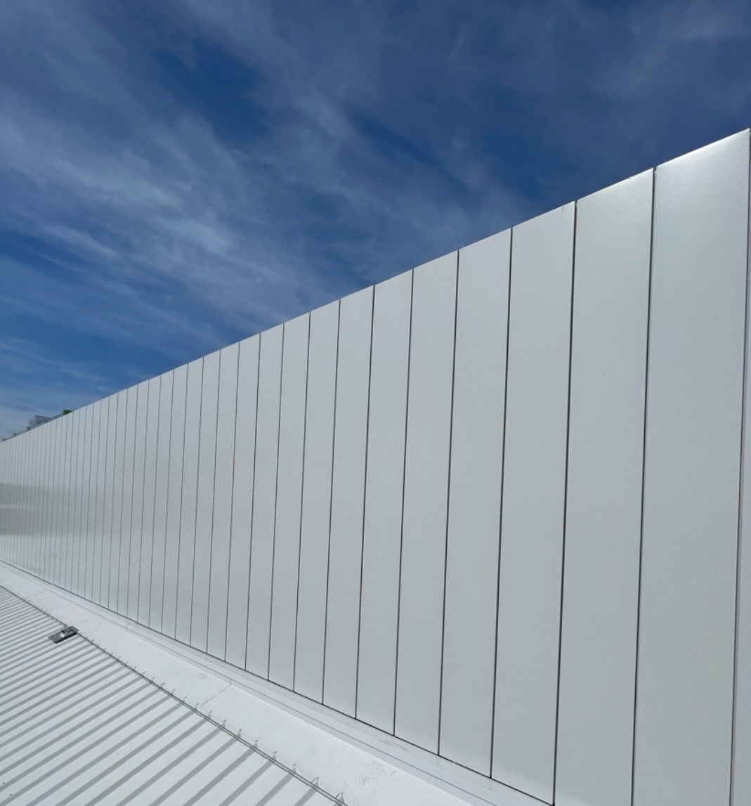 White acoustic wall panels beside a steel-grating rooftop walkway.
