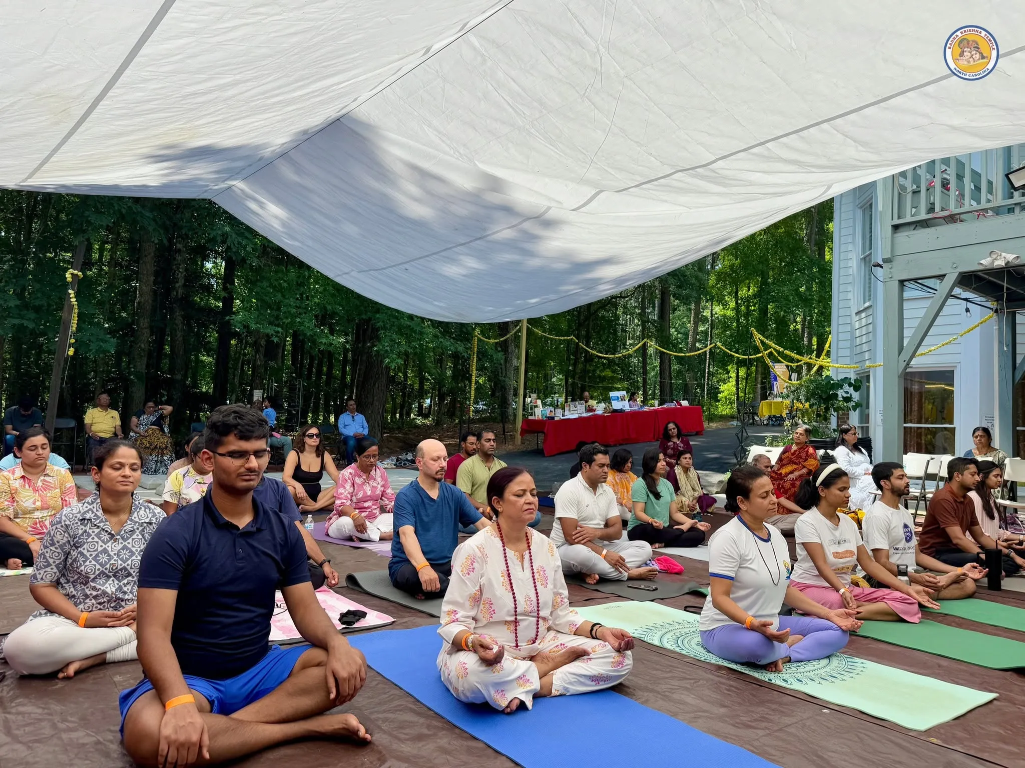 Participants in seated meditation under tent canopy at RKTNC NC Yoga Fest