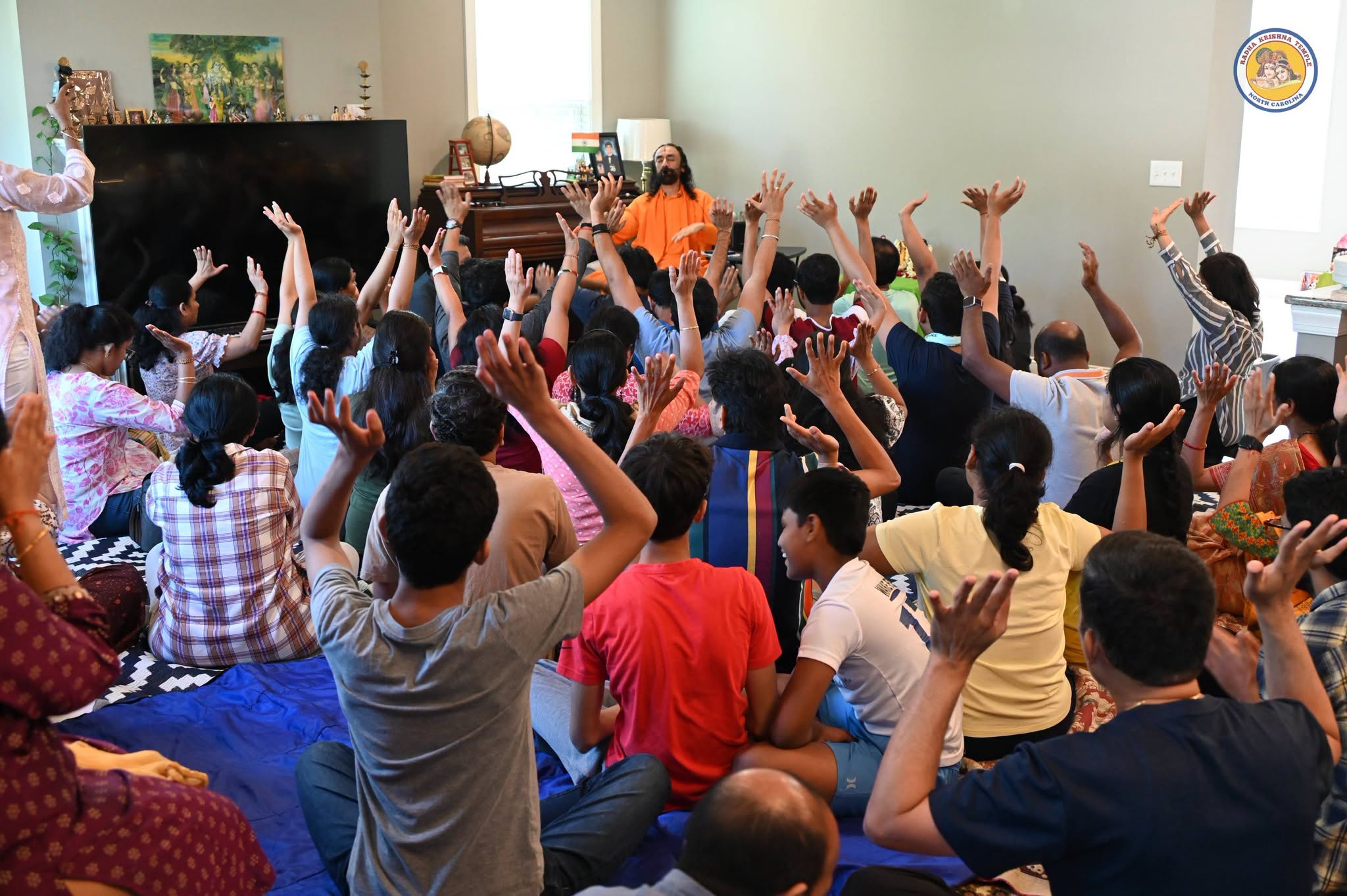 Devotees joyfully singing kirtan during a satsang with Swami Mukundananda at RKTNC