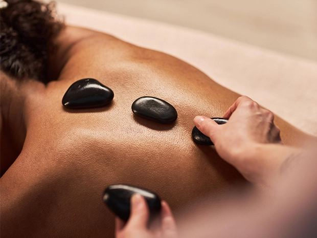 A woman receiving a hot stone massage on her back.