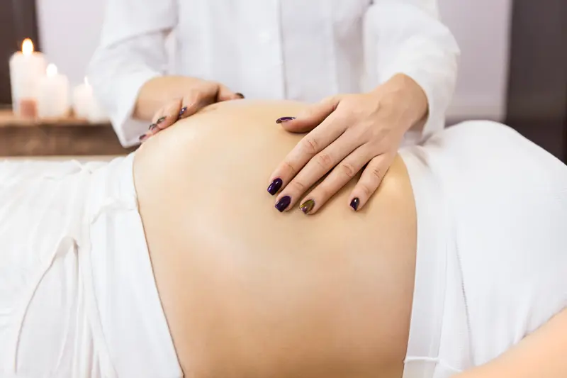 A woman receiving a prenatal massage from gentle hands. 