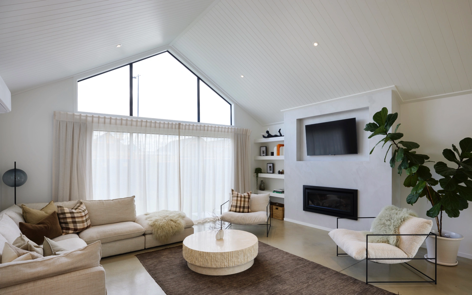 Built in entertainment unit, cladding on ceiling, pitched roof design interior, living room inspiration, concrete flooring, living room rug
