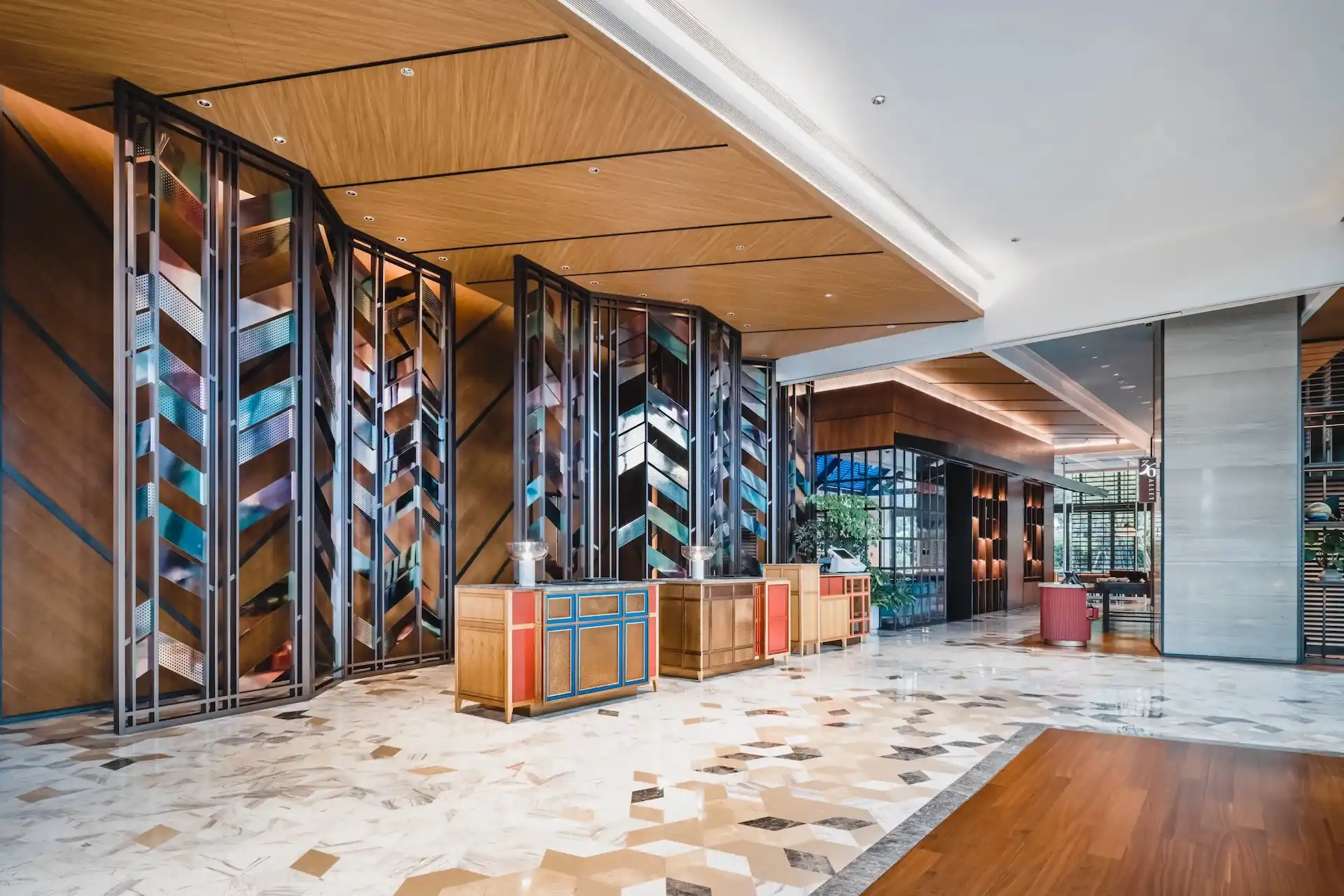 Hyatt Centric Xiamen hotel lobby featuring contemporary timber ceiling panels, geometric marble flooring, custom metal screens and curated reception counters inspired by local culture