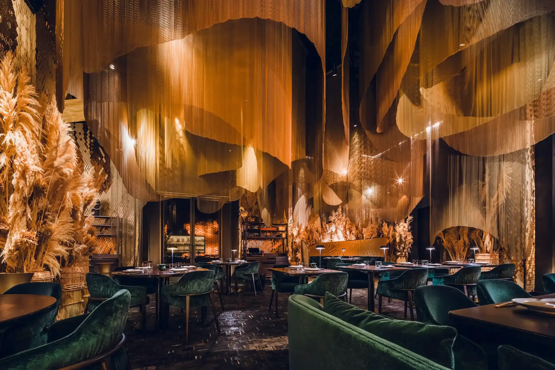 Strawfire Emirates Palace Abu Dhabi main dining area with suspended mesh canopy, draped ceiling fabric and green velvet seating.