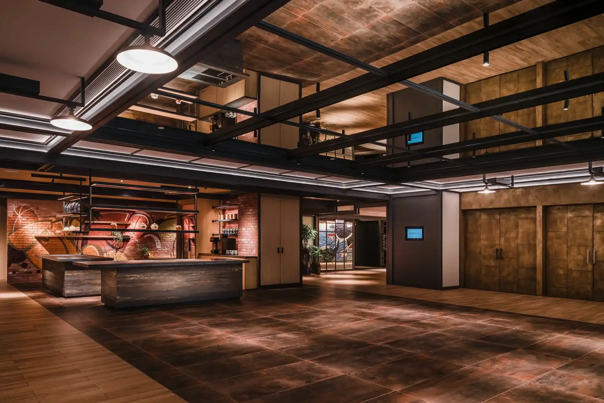 Lobby interior at Hyatt Centric Kuala Lumpur featuring exposed steel beams, industrial ceiling detailing, brick feature wall, reception counter and timber flooring reflecting the hotel’s urban industrial design concept.