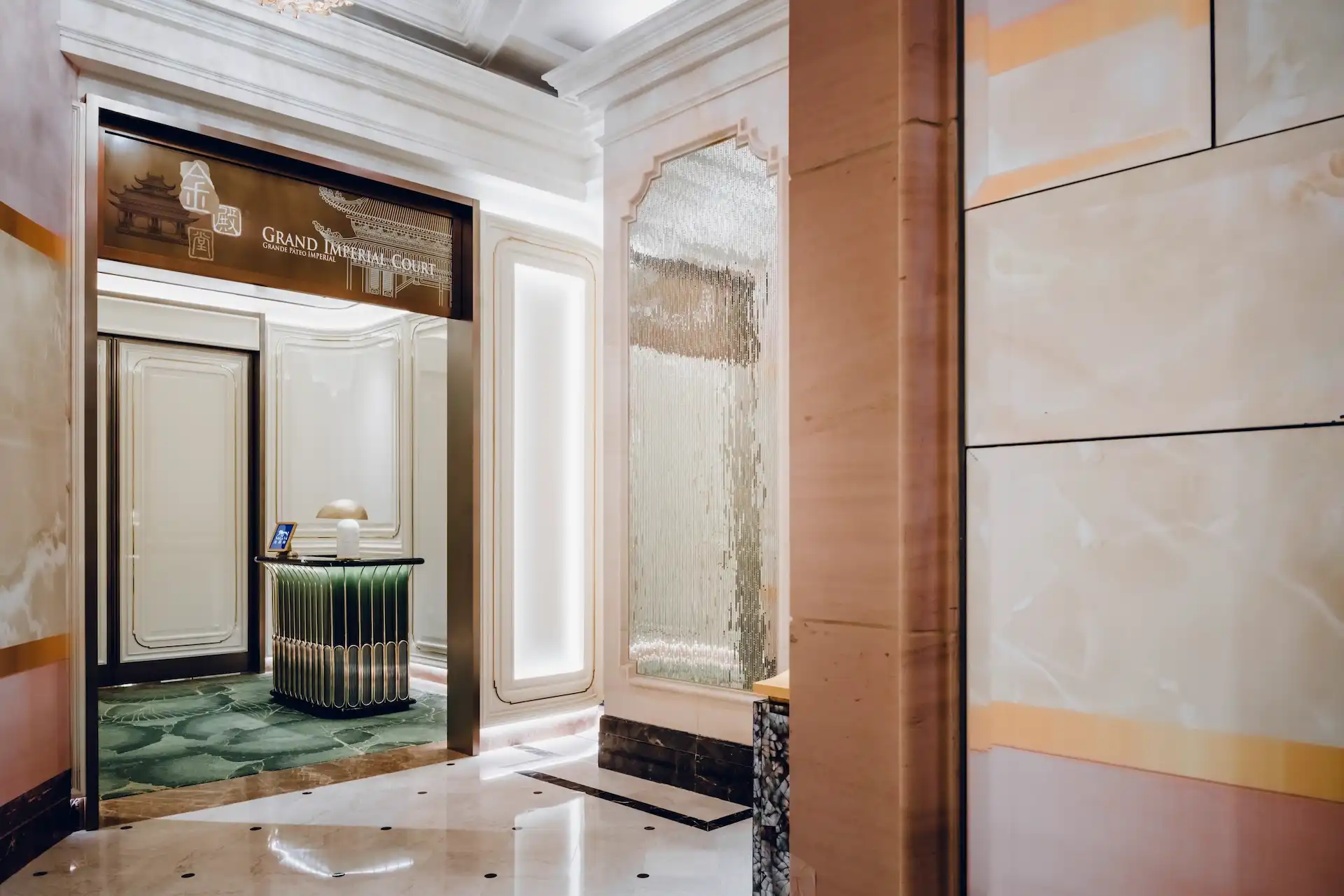 Grand Imperial Court entrance at MGM Macao featuring framed doorway signage green marble flooring sculptural host podium and refined classical wall detailing within a luxury Chinese restaurant setting