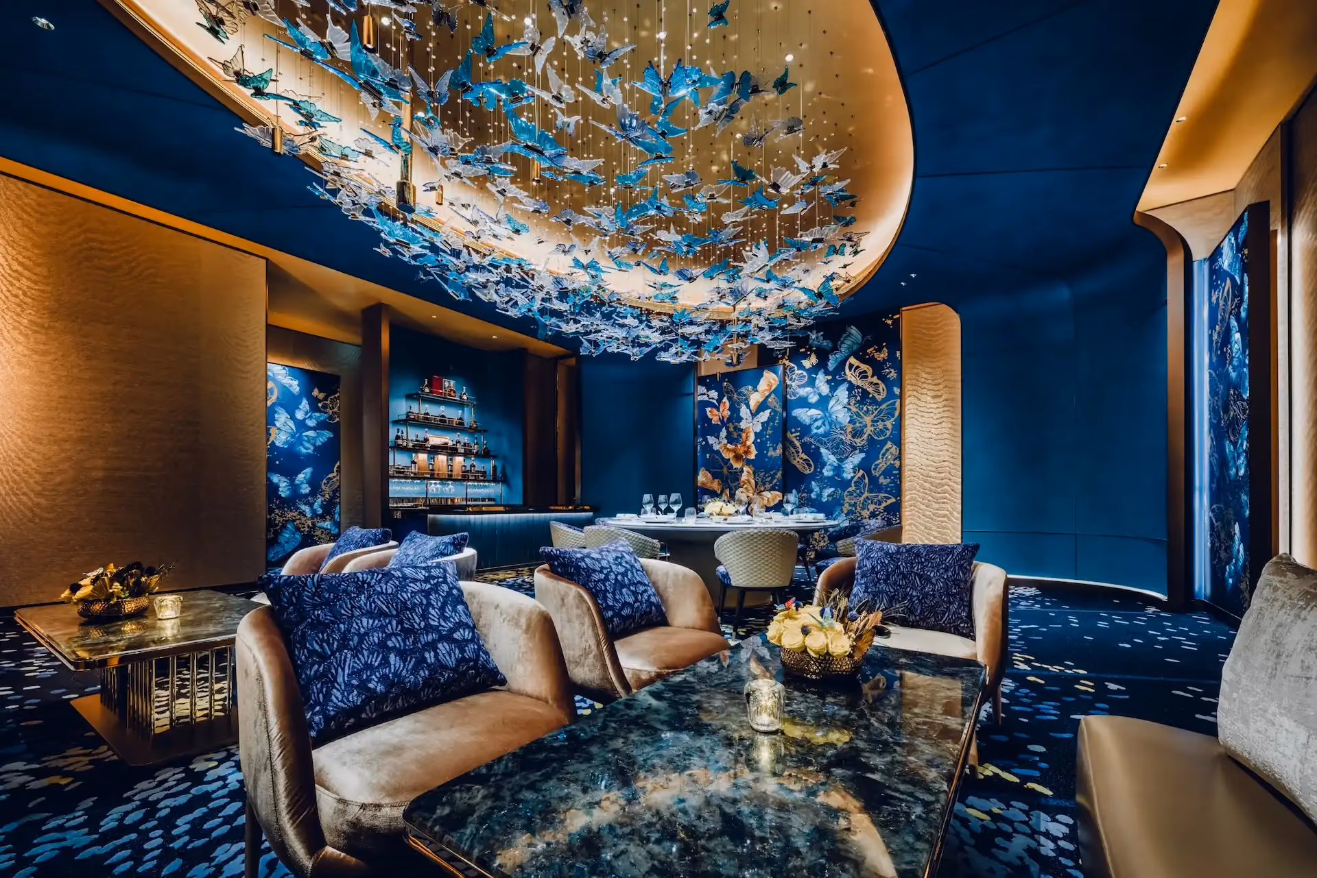 Grand Imperial Court Tapestry Butterfly Wings private dining lounge at MGM Macao featuring deep blue curved wall panels bespoke butterfly artwork illuminated oval ceiling detail suspended butterfly chandelier marble dining table and upholstered seating within a luxury Chinese restaurant interior design