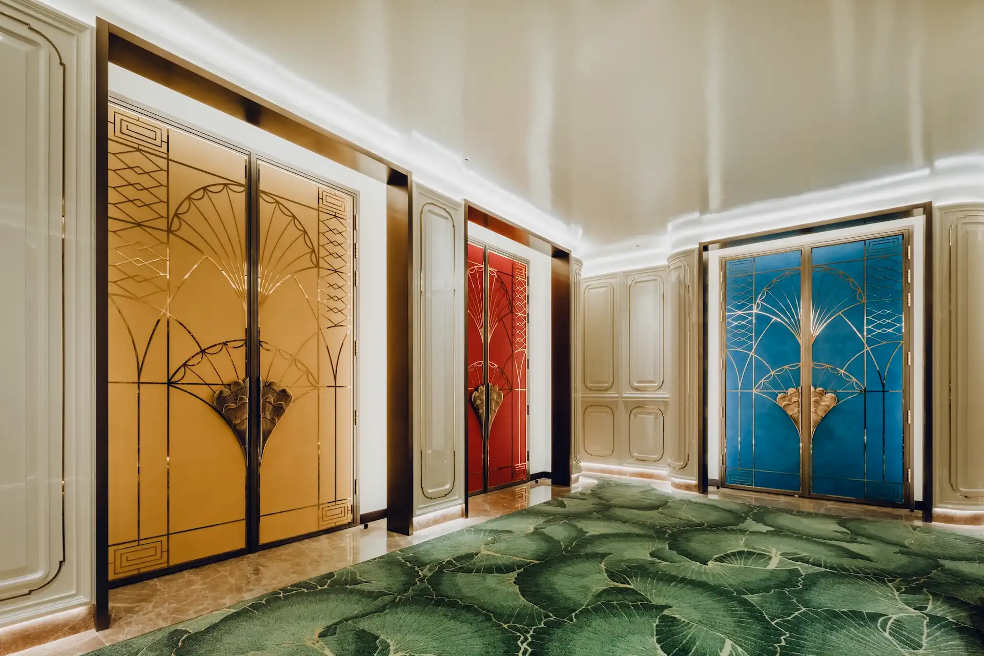 Grand Imperial Court private dining room entrances at MGM Macao featuring colour coded lacquer doors in gold red and blue with brass fan motif detailing ivory wall panels and bespoke green leaf patterned carpet within a luxury Chinese restaurant interior