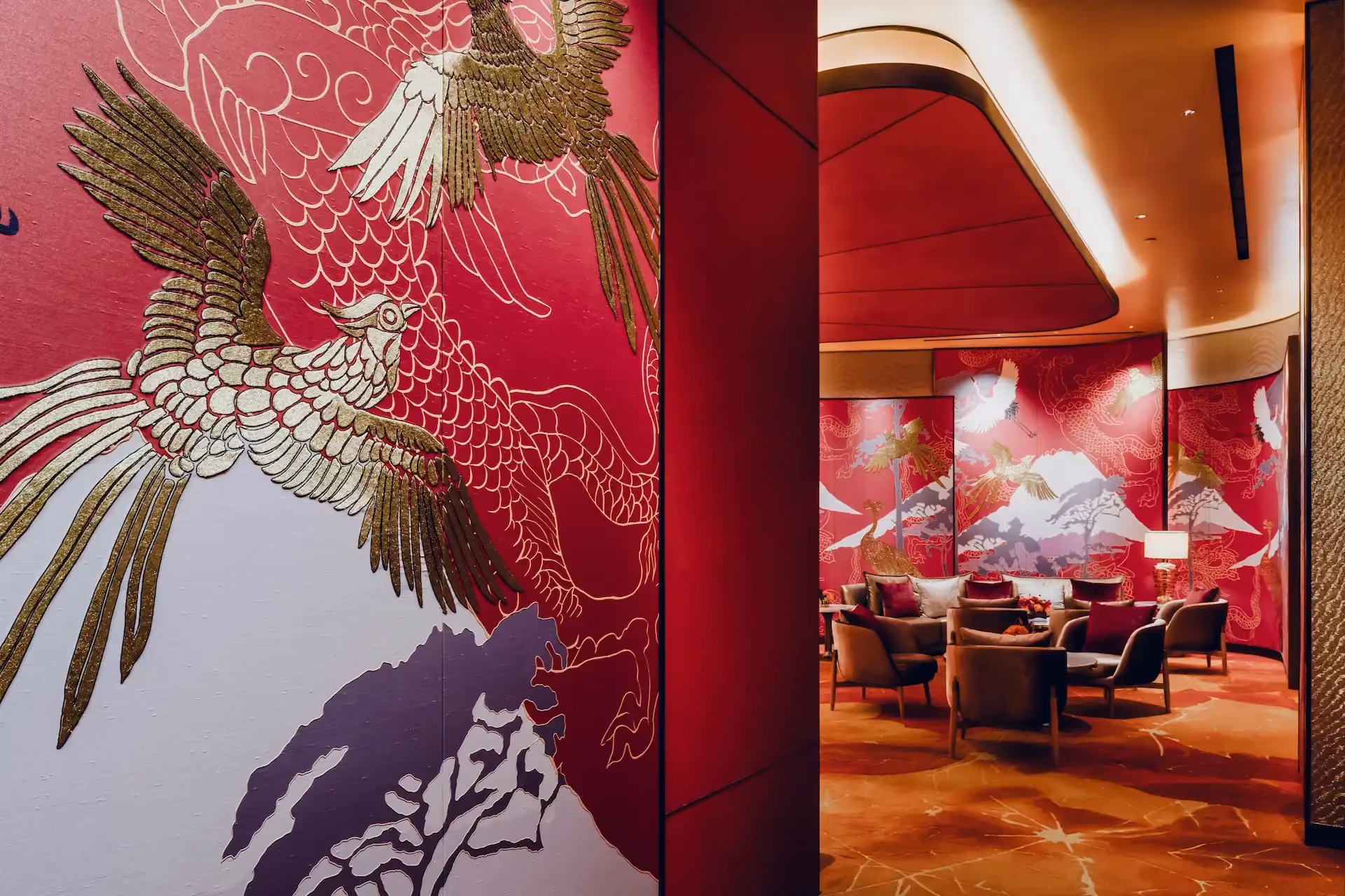 Grand Imperial Court Tapestry Of Parchment private lounge at MGM Macao featuring red lacquered wall panels with gold phoenix artwork mountain motif detailing curved ceiling recess bespoke patterned carpet and intimate lounge seating within a luxury Chinese restaurant interior design
