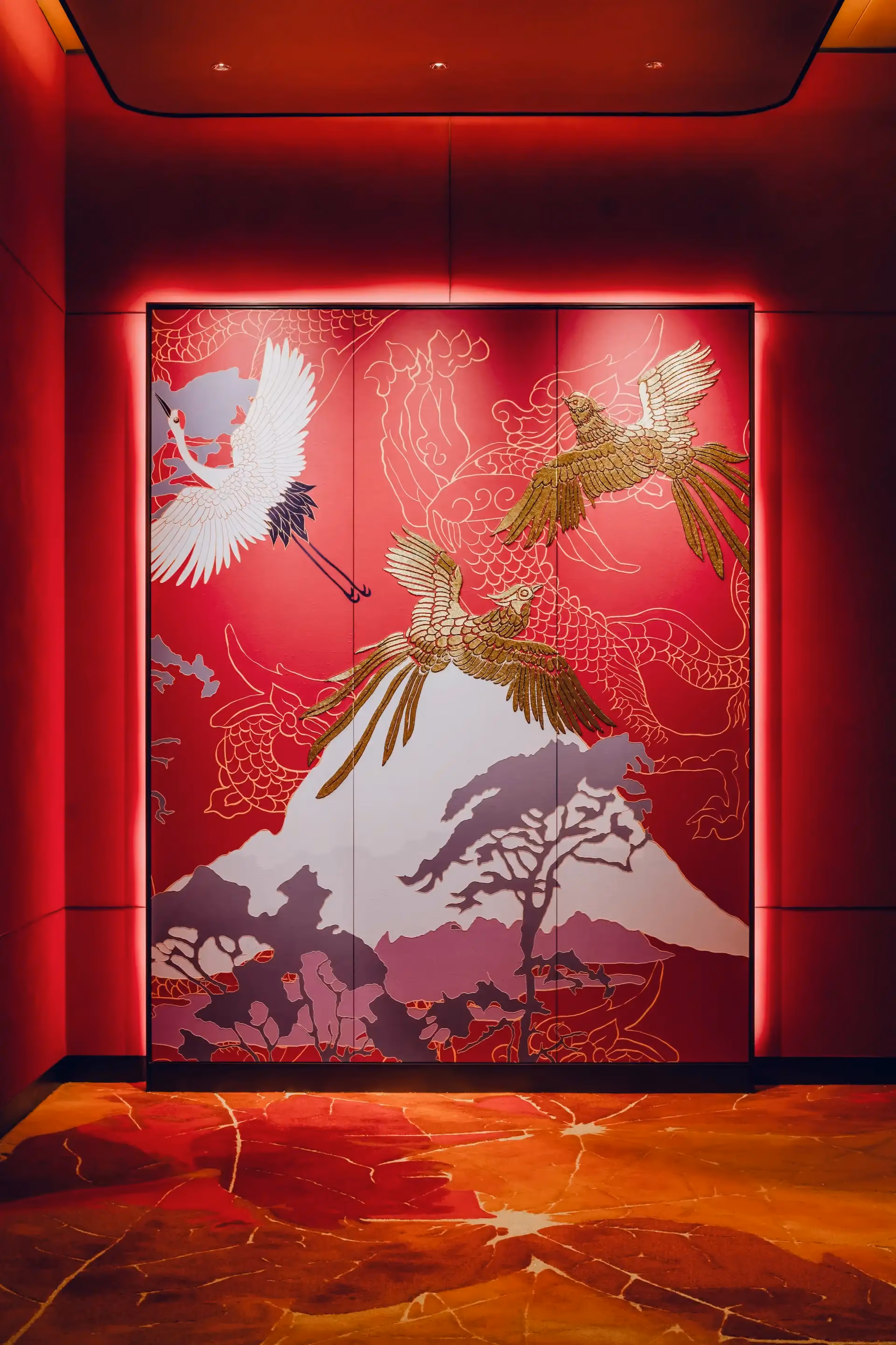 Grand Imperial Court Tapestry Of Parchment entrance feature at MGM Macao showcasing illuminated red wall panels with gold phoenix and crane artwork mountain motif detailing and bespoke patterned flooring within a luxury Chinese restaurant interior design