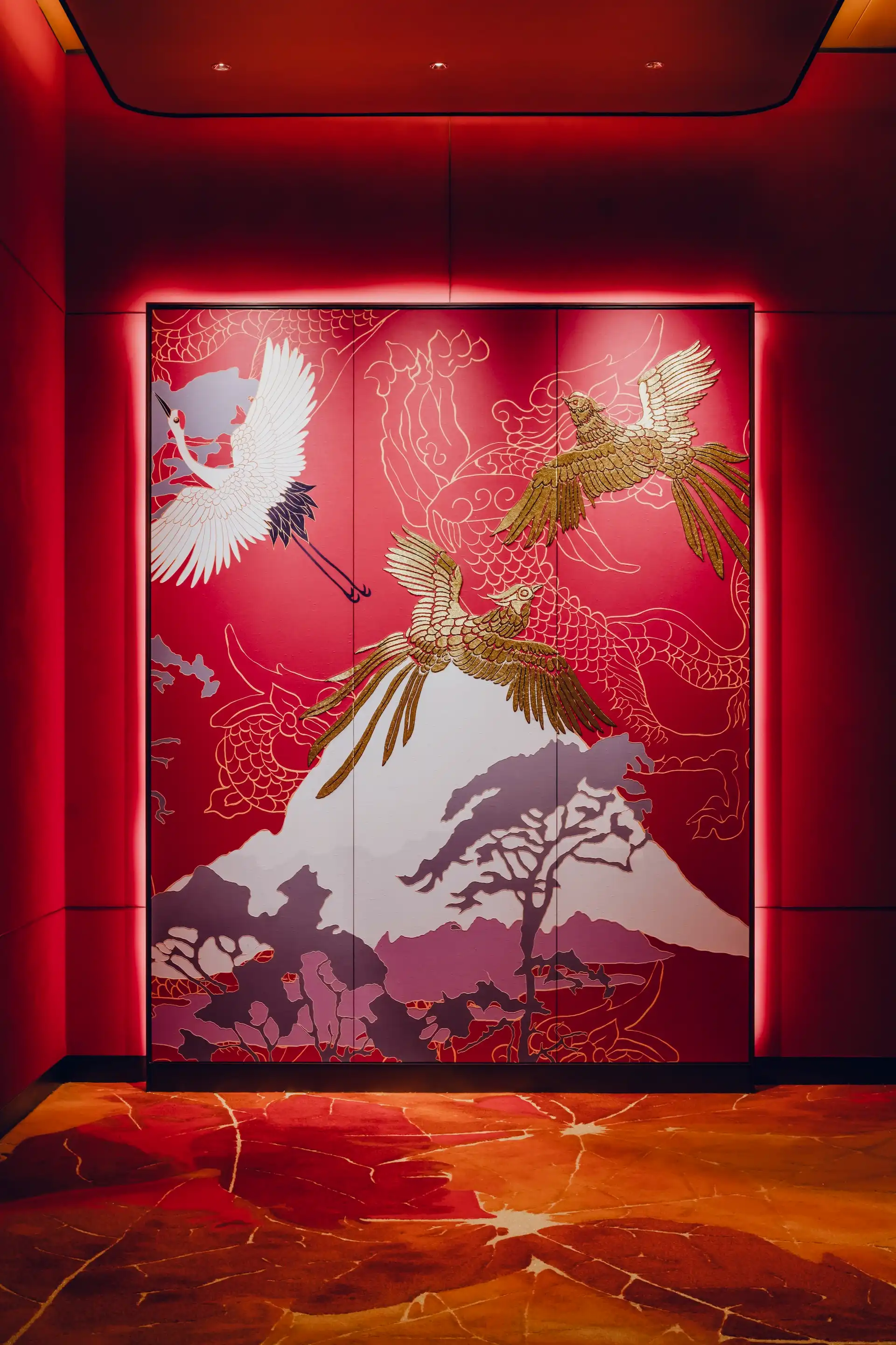 Grand Imperial Court Tapestry Of Parchment entrance feature at MGM Macao showcasing illuminated red wall panels with gold phoenix and crane artwork mountain motif detailing and bespoke patterned flooring within a luxury Chinese restaurant interior design