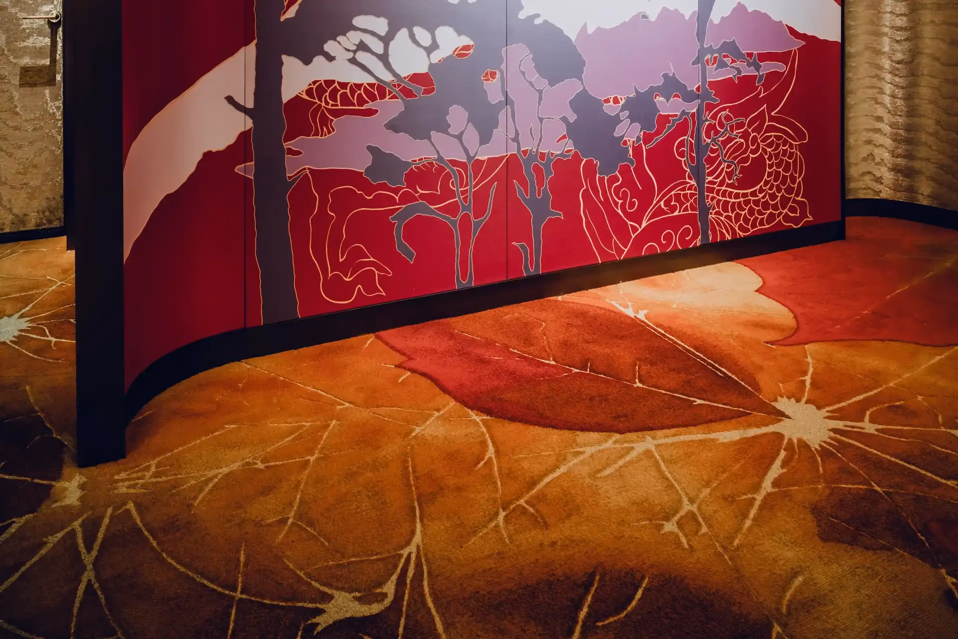 Grand Imperial Court Tapestry Of Parchment custom carpet detail at MGM Macao featuring bespoke leaf motif flooring in red and bronze tones beneath illuminated red lacquer wall panels with gold linework within a luxury Chinese restaurant interior design