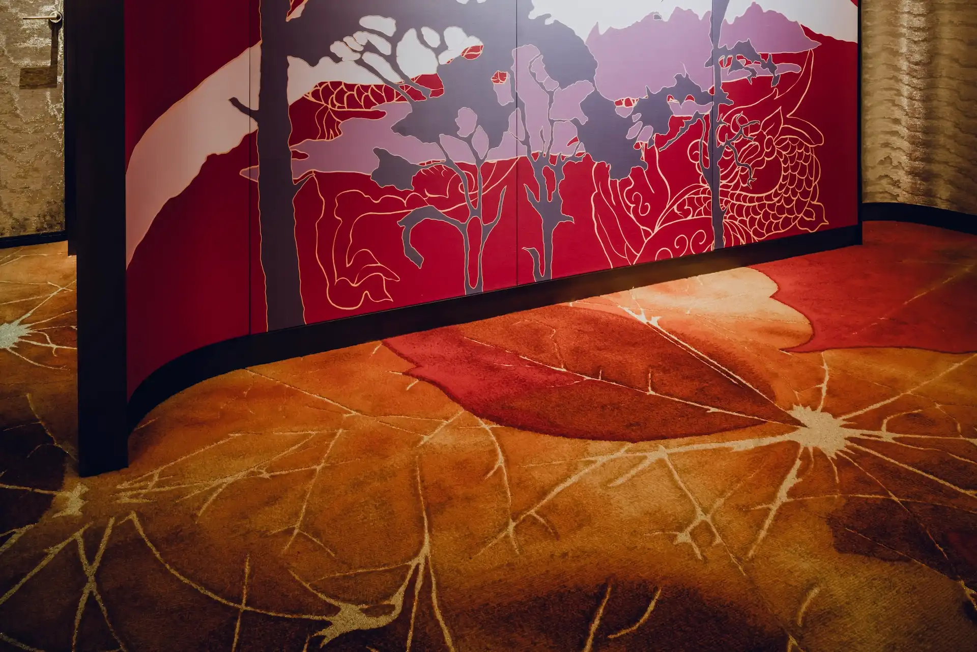 Grand Imperial Court Tapestry Of Parchment custom carpet detail at MGM Macao featuring bespoke leaf motif flooring in red and bronze tones beneath illuminated red lacquer wall panels with gold linework within a luxury Chinese restaurant interior design