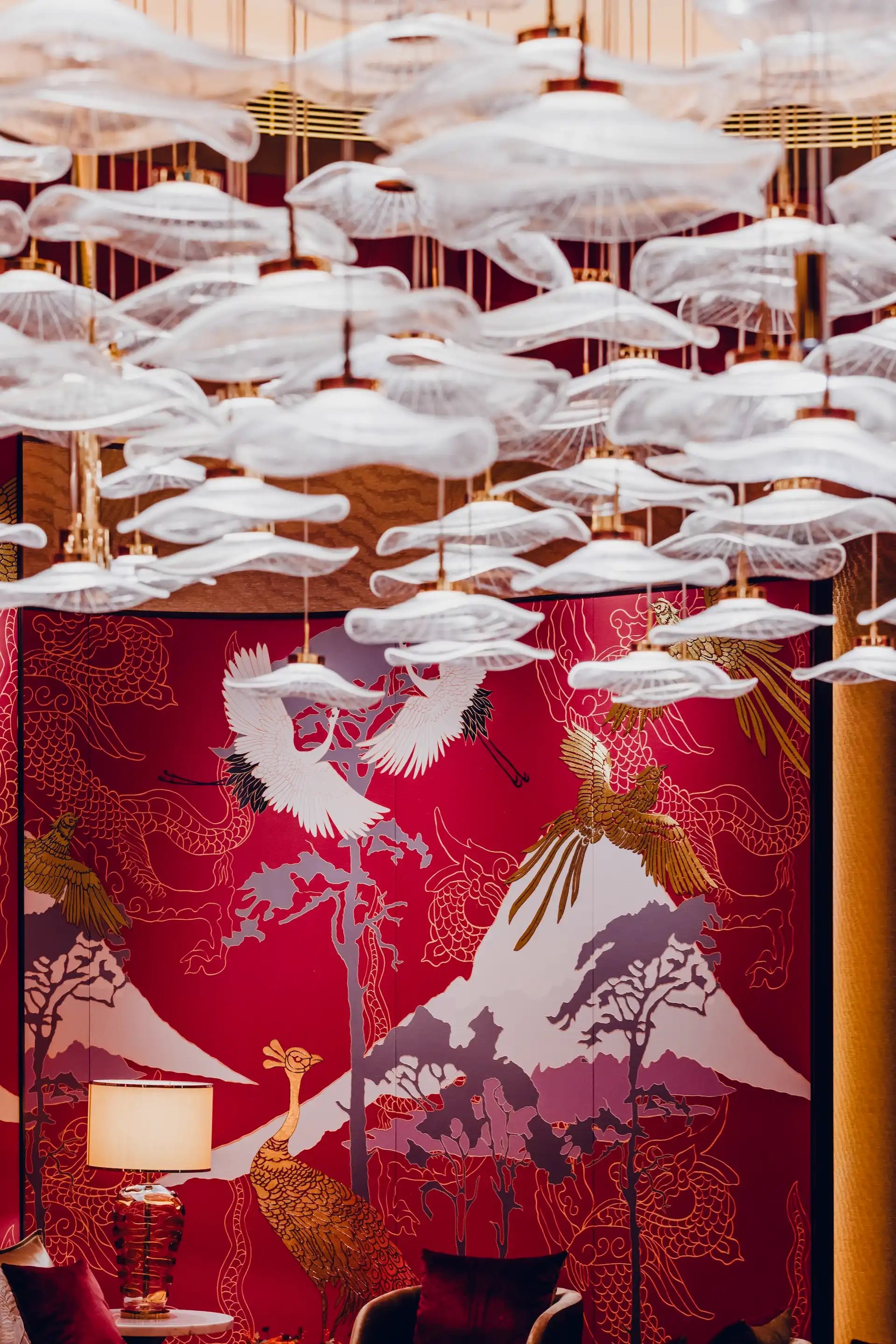 Grand Imperial Court Tapestry Of Parchment private dining interior at MGM Macao featuring suspended layered glass pendant installation above red lacquer wall panels with gold and white phoenix murals, mountain landscape motifs and bespoke luxury Chinese restaurant detailing
