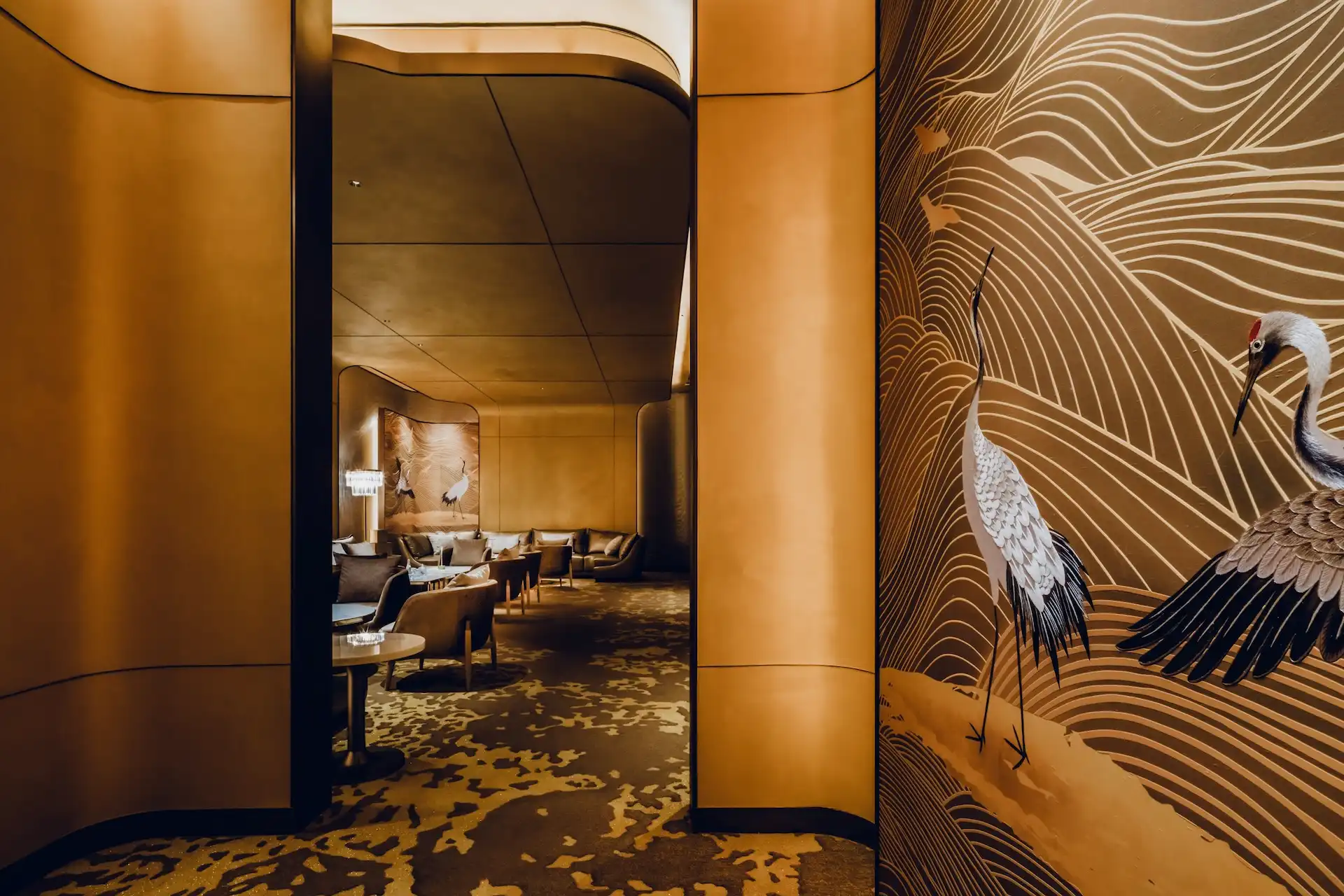 Grand Imperial Court corridor at MGM Macao featuring illuminated gold wall panels and crane mural artwork with flowing line motifs leading into a private lounge seating area, expressing layered spatial planning within a luxury Chinese restaurant interior