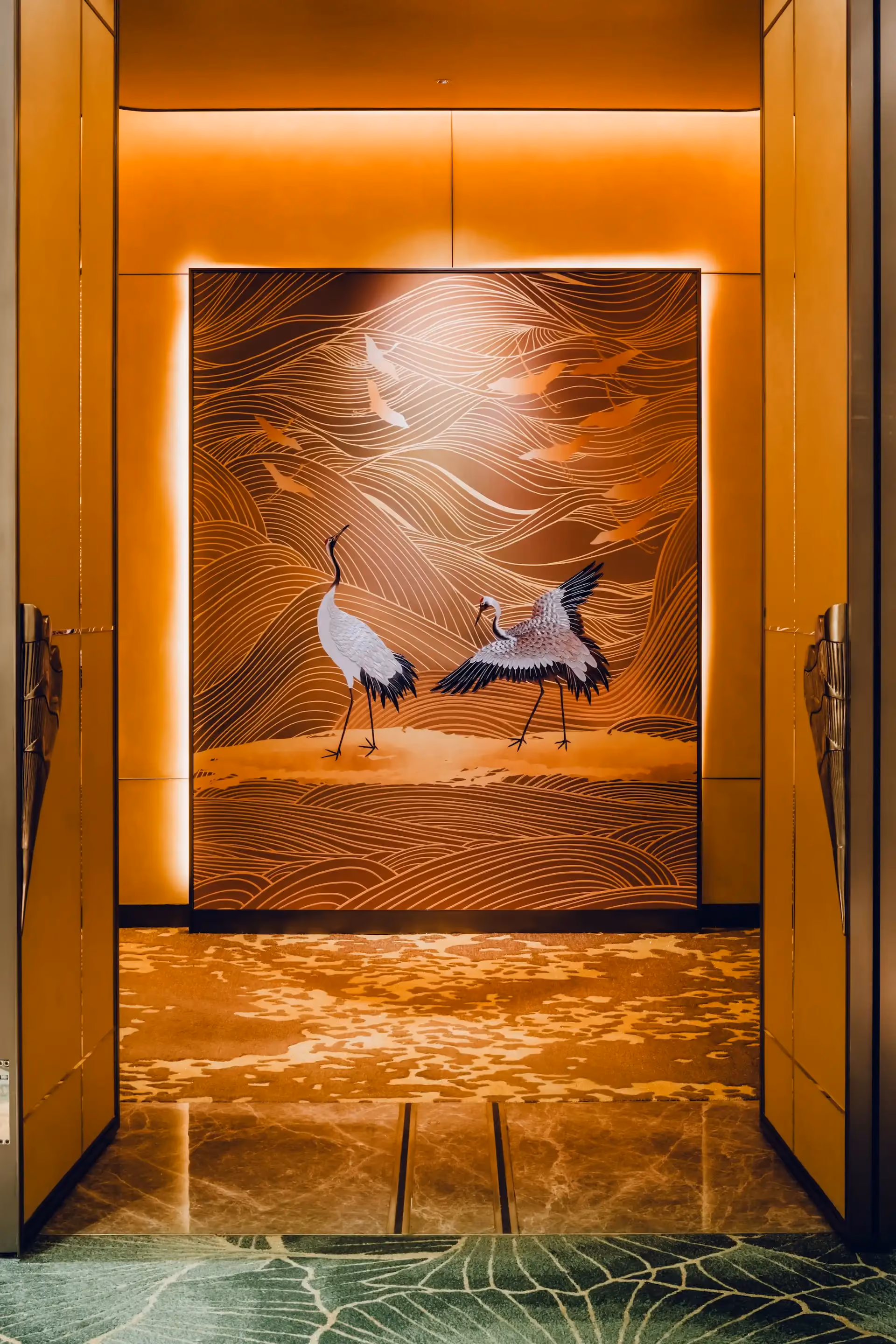 Grand Imperial Court entrance feature panel at MGM Macao showcasing illuminated gold crane artwork with flowing line motifs and layered landscape pattern framed by bespoke gold doors, forming a ceremonial threshold within a luxury Chinese restaurant interior