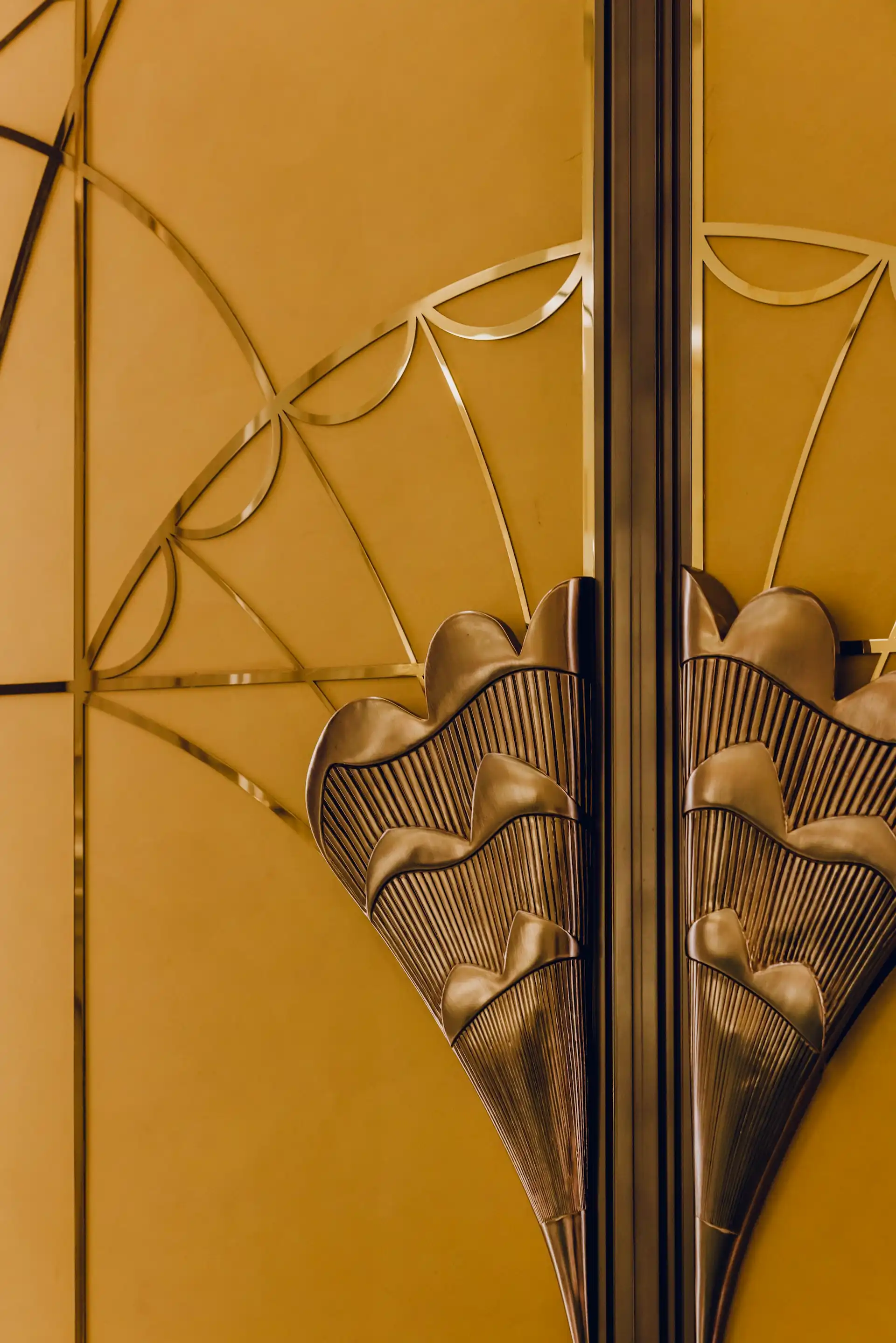 Grand Imperial Court Tapestry Of Gold Leaves entrance door handle detail at MGM Macao featuring sculpted brass leaf motif handles mounted on gold panelled doors with geometric metal inlay, expressing bespoke craftsmanship within a luxury Chinese restaurant interior