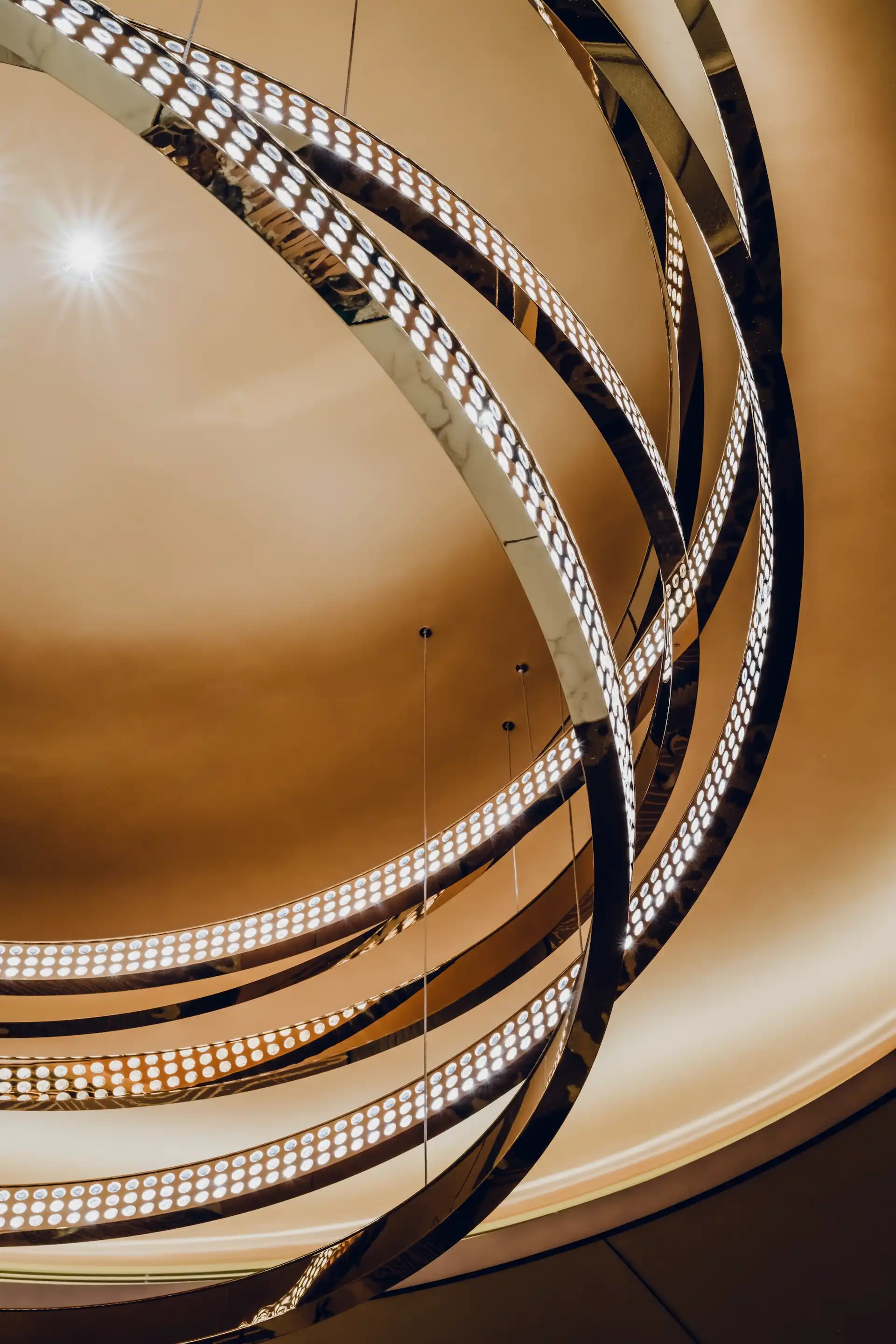 Grand Imperial Court circular chandelier lighting detail at MGM Macao featuring interwoven illuminated metal rings with integrated LED points suspended within a recessed ceiling dome, expressing bespoke contemporary lighting design in a luxury Chinese restaurant interior