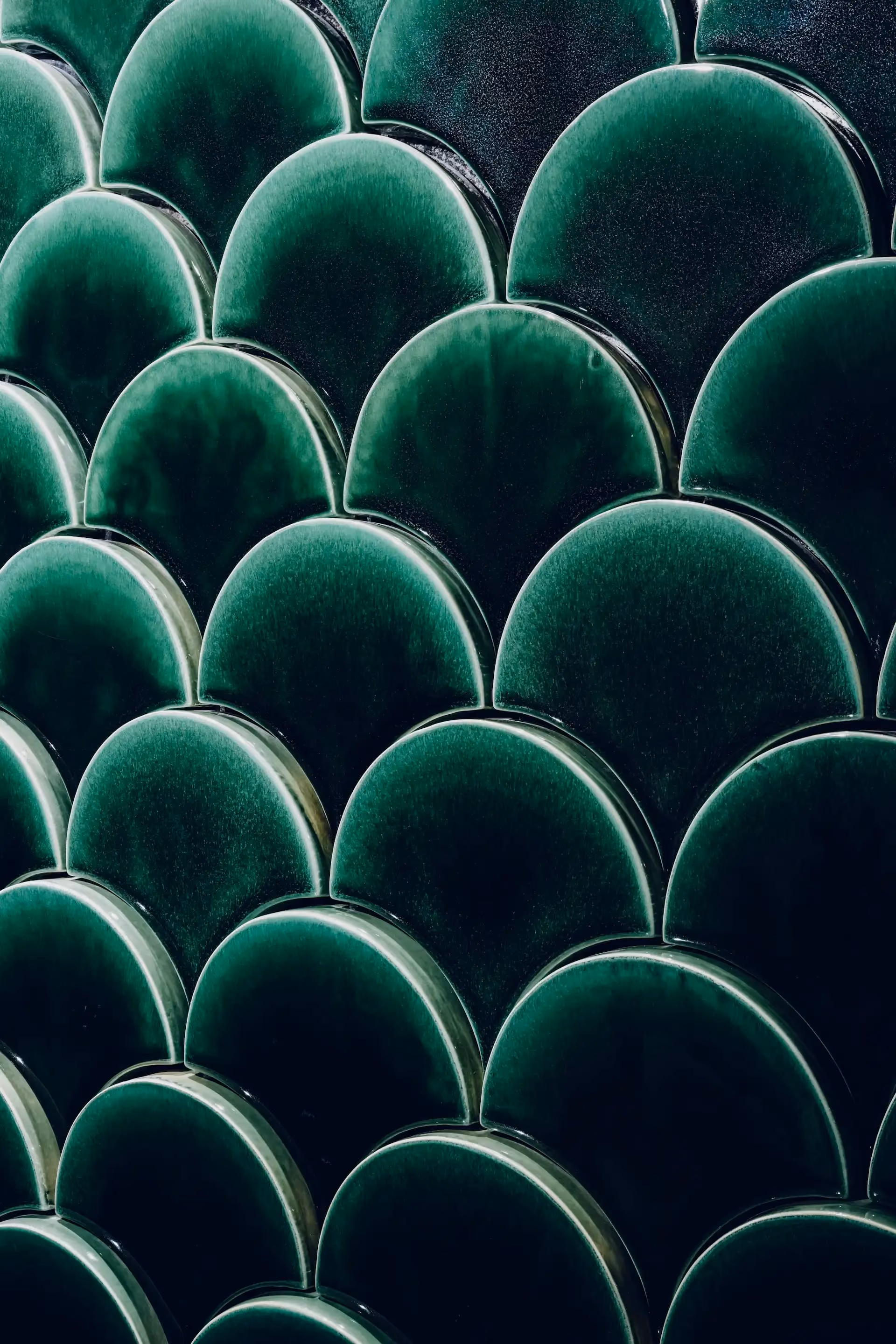 Close up of deep green scalloped ceramic wall tiles in Tapestry of Feathers restroom at Grand Imperial Court MGM Macau with glossy finish and layered feather inspired pattern.