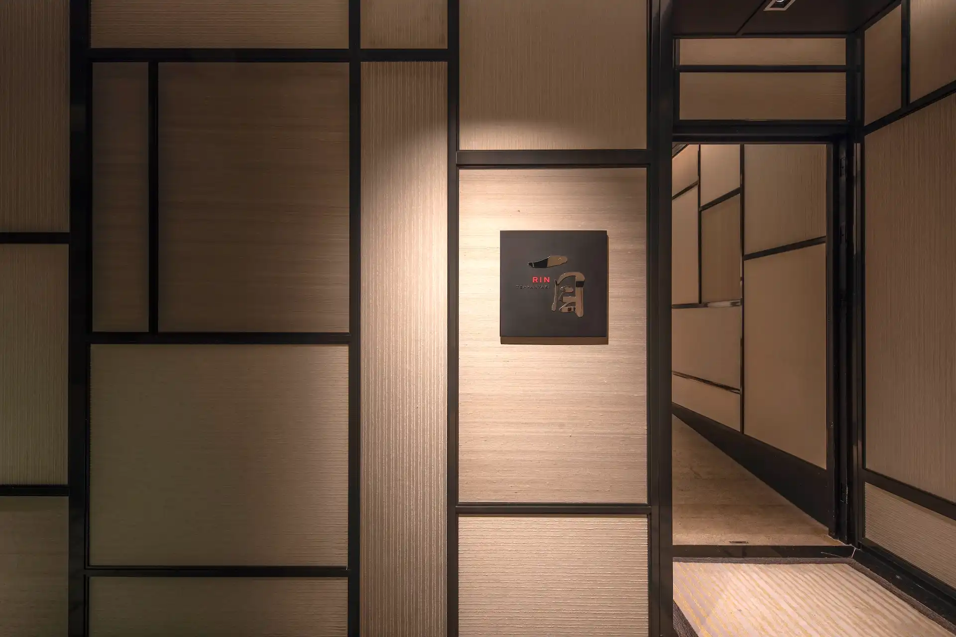 Entrance to RIN restaurant at Mandarin Oriental Shenzhen featuring textured wall panels, black framed architectural detailing and illuminated RIN signage within a refined Japanese inspired interior setting.