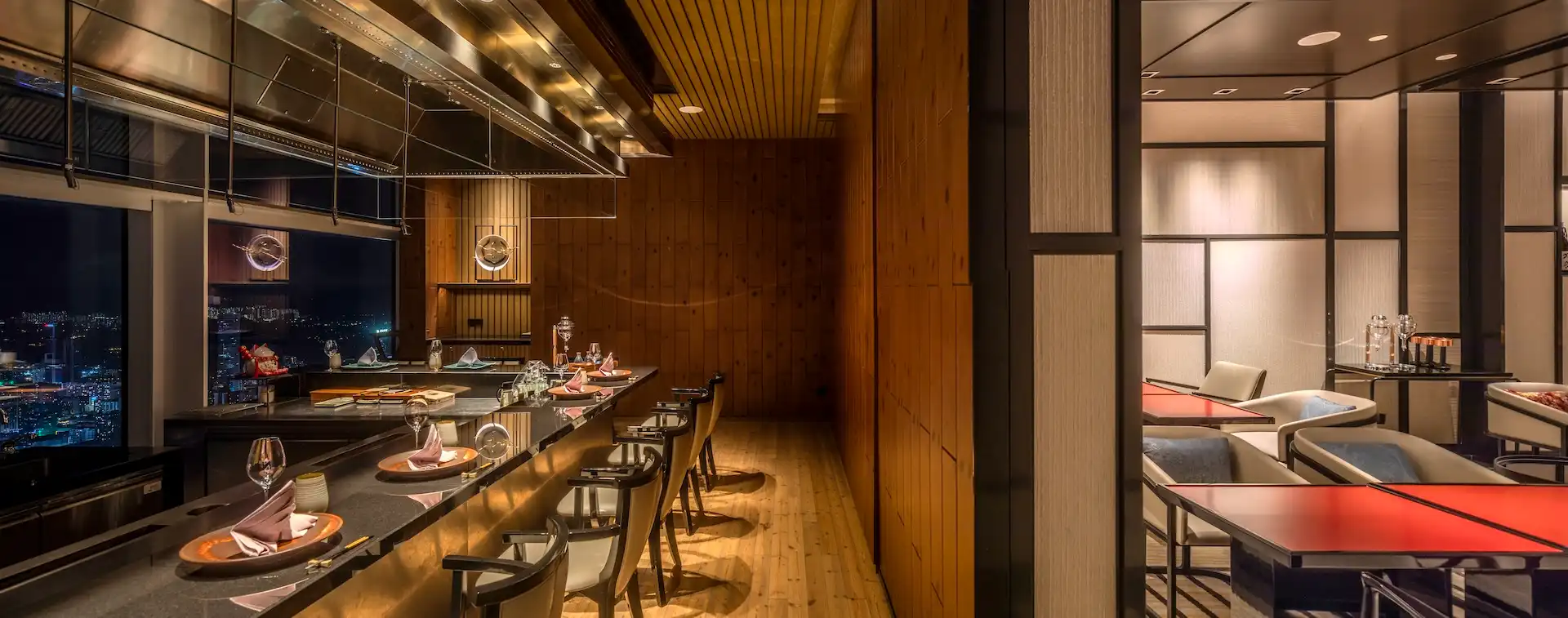 Split interior view at RIN Mandarin Oriental Shenzhen showing the Pine Room teppanyaki counter with timber wall paneling and granite chef station alongside the adjoining sake lounge with red lacquer tables, upholstered lounge seating, and Japanese panel detailing.