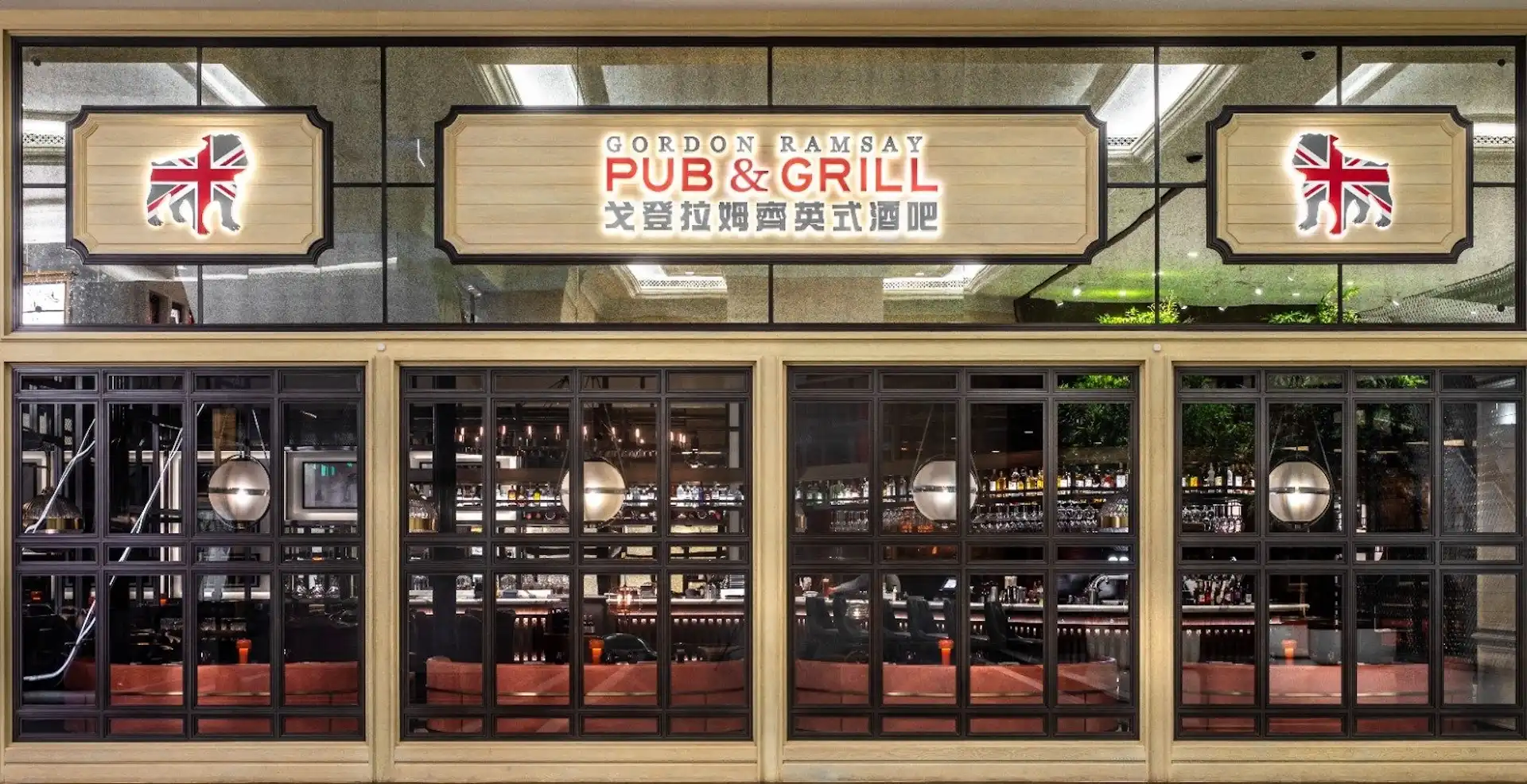 Facade of Gordon Ramsay Pub & Grill at The Londoner Macao featuring illuminated Gordon Ramsay Pub & Grill signage, Union Jack lion emblems, large steel framed windows revealing the bar interior, and a British pub inspired frontage within The Londoner Macao complex.