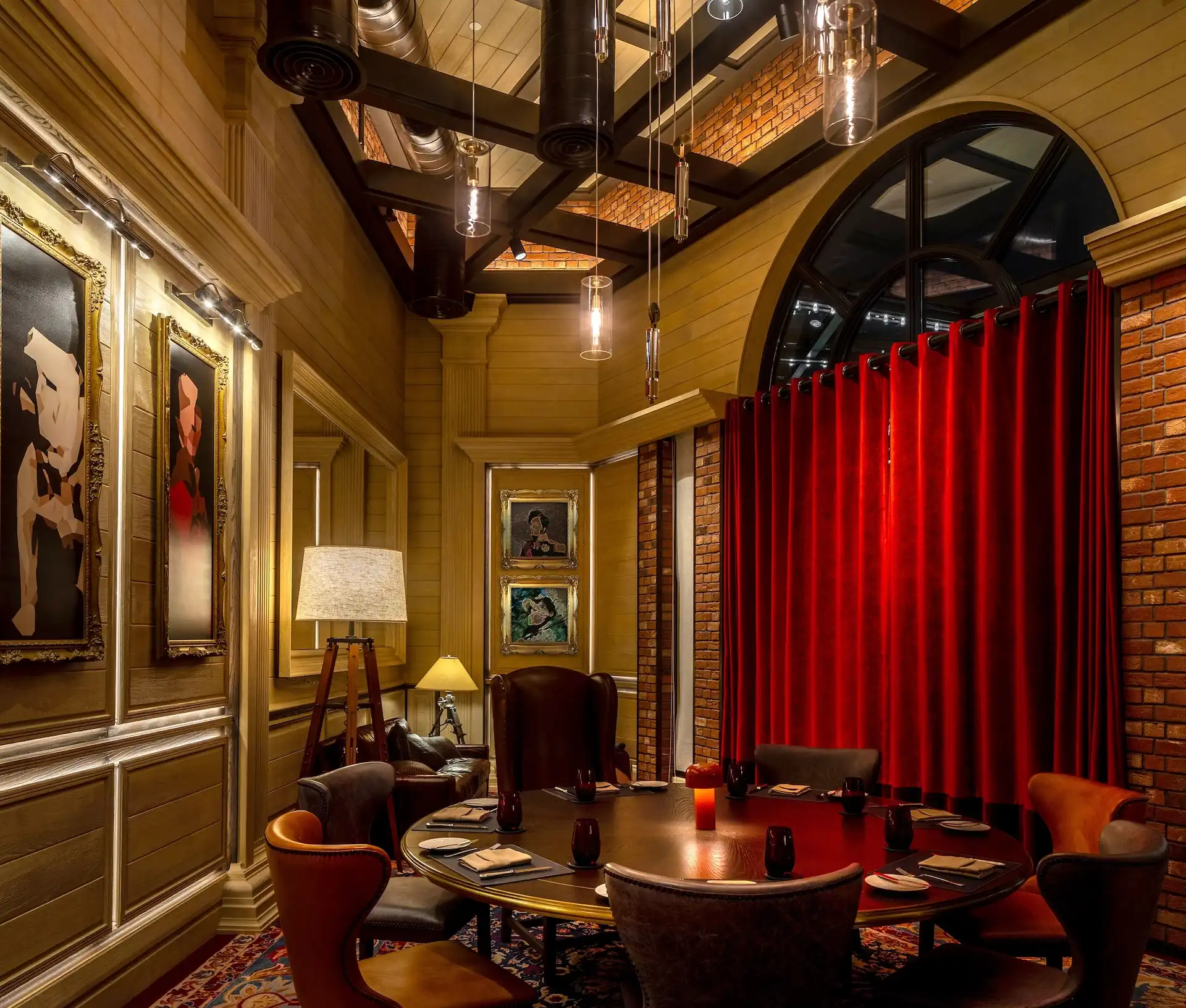 Private dining room at Gordon Ramsay Pub & Grill at The Londoner Macao featuring a round timber dining table, upholstered chairs, red velvet curtains, brick walls, framed artwork, and pendant lighting within an intimate British pub inspired dining setting.