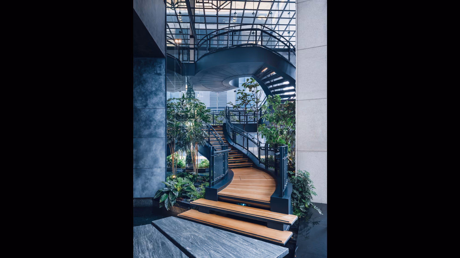 Steel spiral staircase at Hyatt Centric City Centre Kuala Lumpur, with timber treads and a mirror-framed annex reflecting the structure