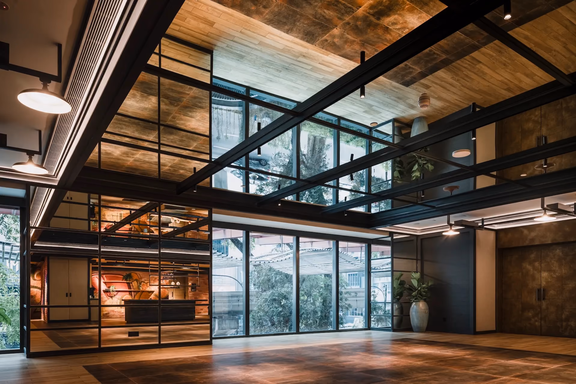 Level 1 breakout area at Hyatt Centric City Centre Kuala Lumpur, with steel-framed glazing, a timber-clad ceiling and views to the trees outside