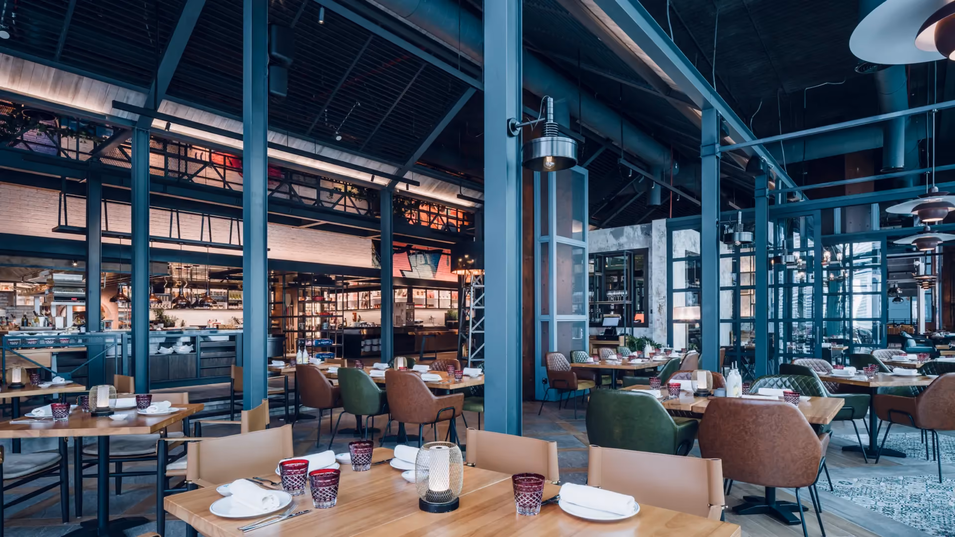 The Gallery dining area at IL Forno, Hyatt Centric City Centre Kuala Lumpur, with teal steel columns, timber tables and the show kitchen beyond