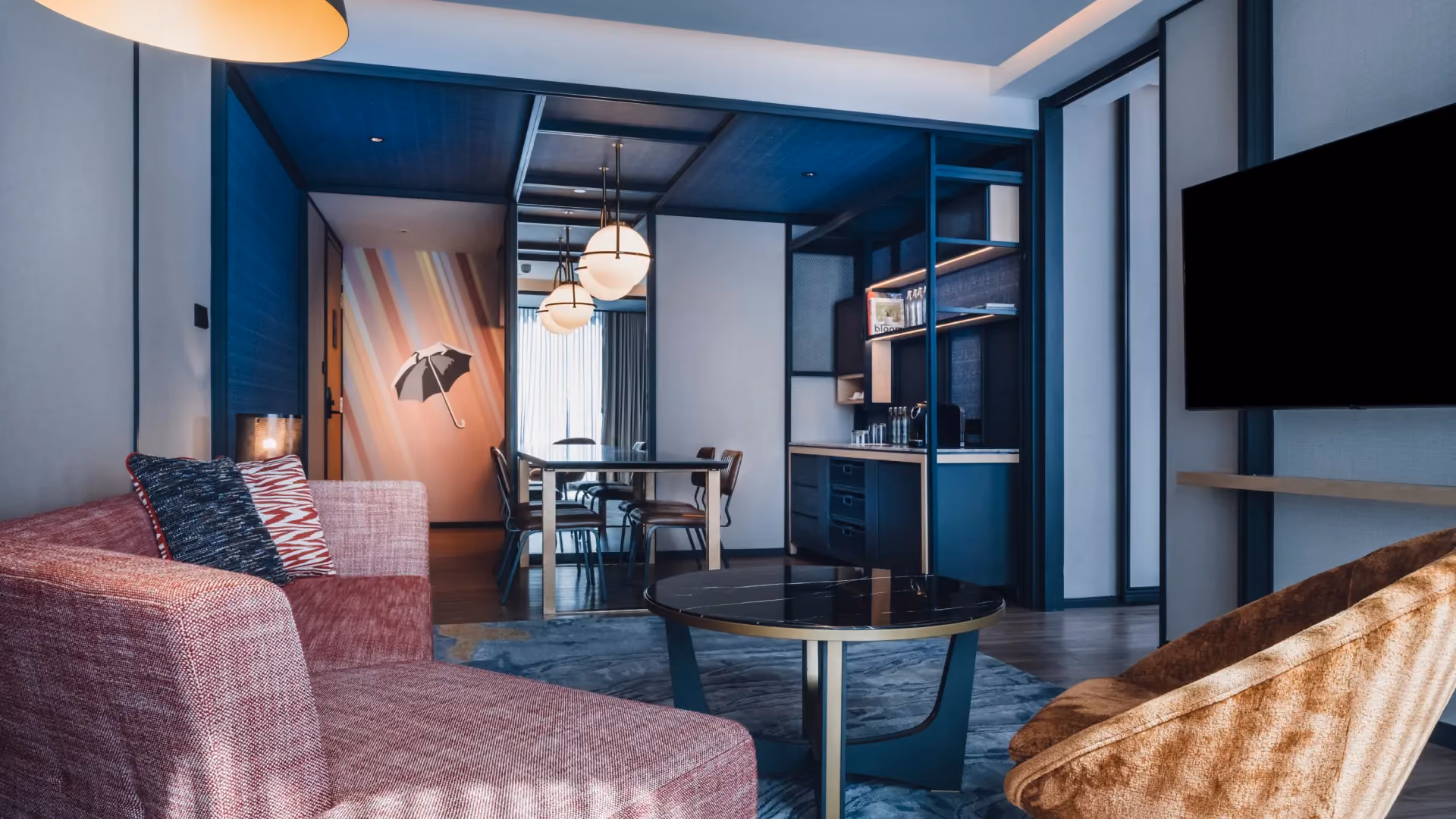 Suite King living room at Hyatt Centric City Centre Kuala Lumpur, with a pink upholstered sofa, denim blue walls and a dining area beyond