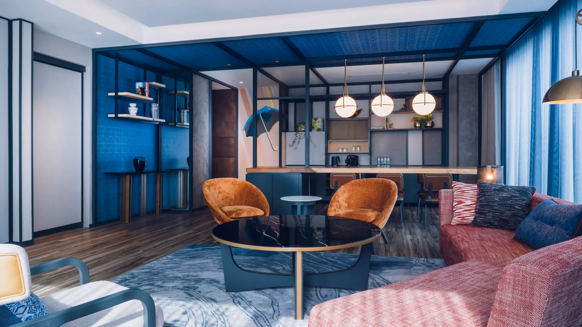 Hospitality Suite at Hyatt Centric City Centre Kuala Lumpur, with denim blue walls, orange armchairs, a pink sofa and globe pendant lights