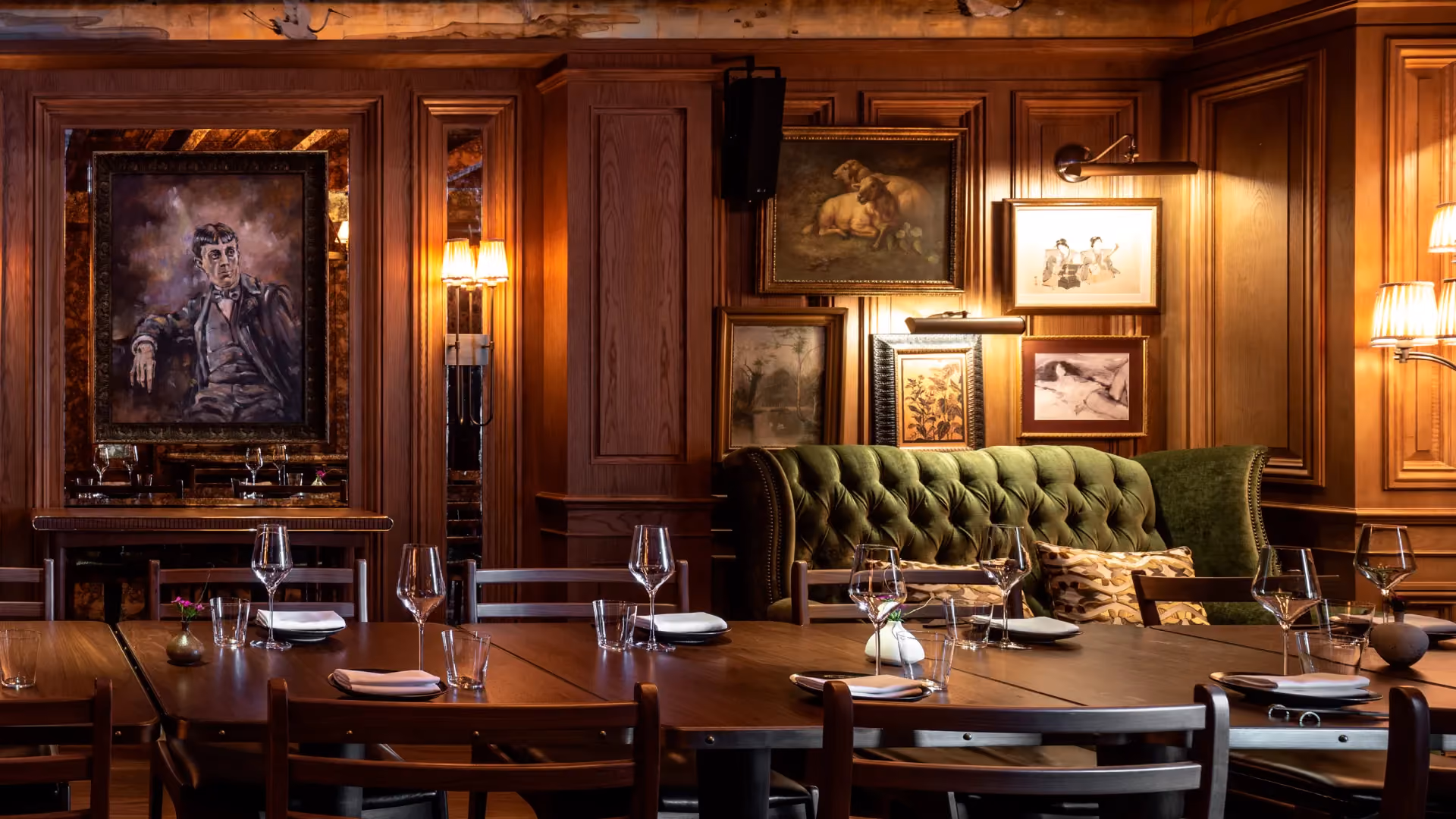 Private dining room at The Aubrey, Mandarin Oriental Hong Kong, with timber panelling, framed portraits, a green tufted banquette and a long dining table
