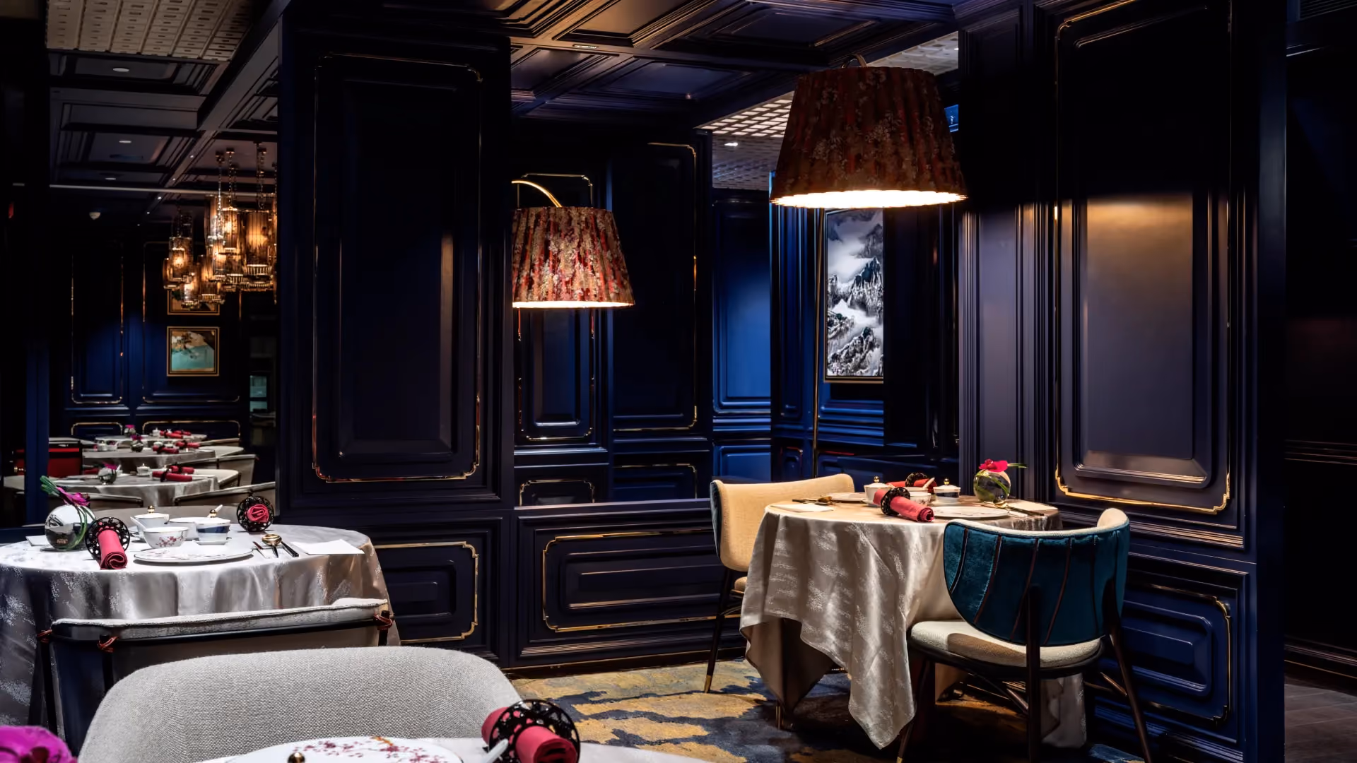Semi-private dining niches at Man Wah, Mandarin Oriental Hong Kong, formed by blue lacquered panelling with pendant lamps and set tables