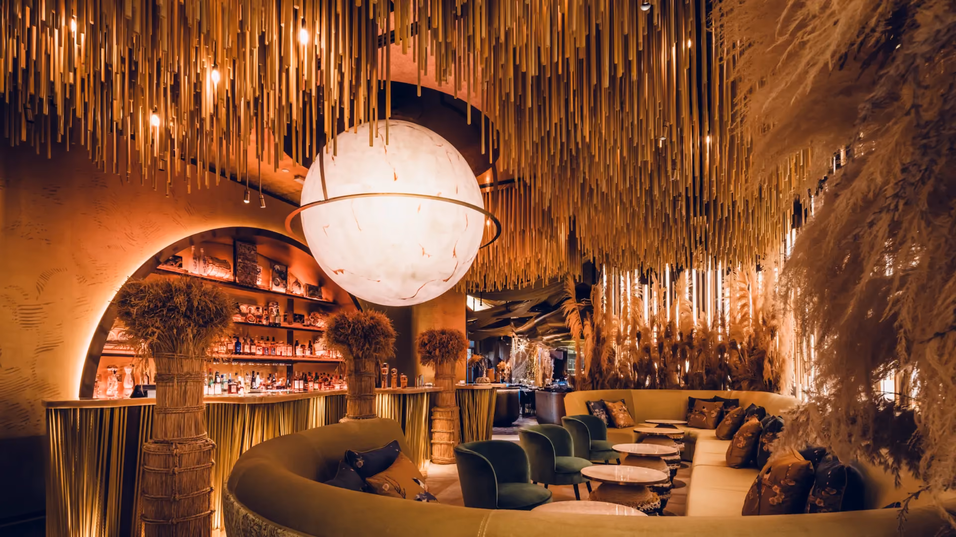 Sake lounge at Strawfire, Emirates Palace Abu Dhabi, with a large glowing globe, suspended golden rods and a gold velvet banquette