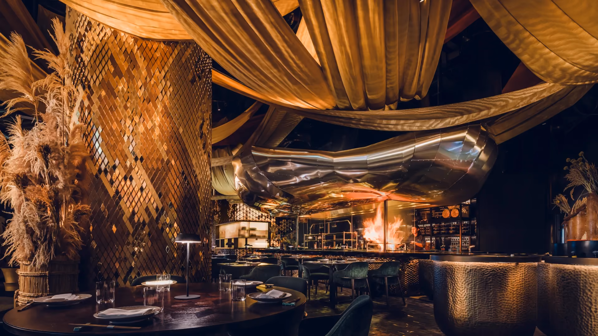 Main dining room at Strawfire, Emirates Palace Abu Dhabi, with draped gold silk canopies, the brass hood over the grill and straw bales
